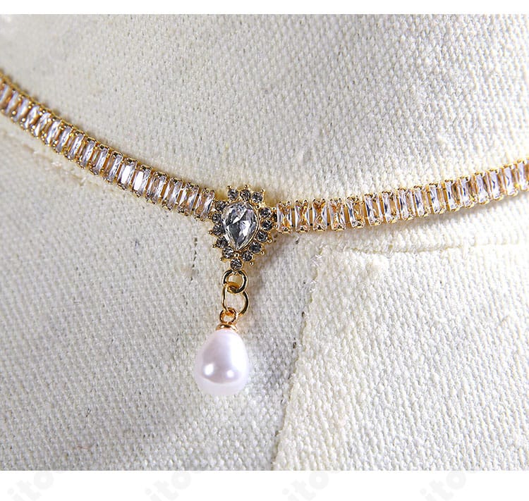 ネック周りの装飾とネックレスの接写。パールリネンの微光沢と留め具の仕上げ。